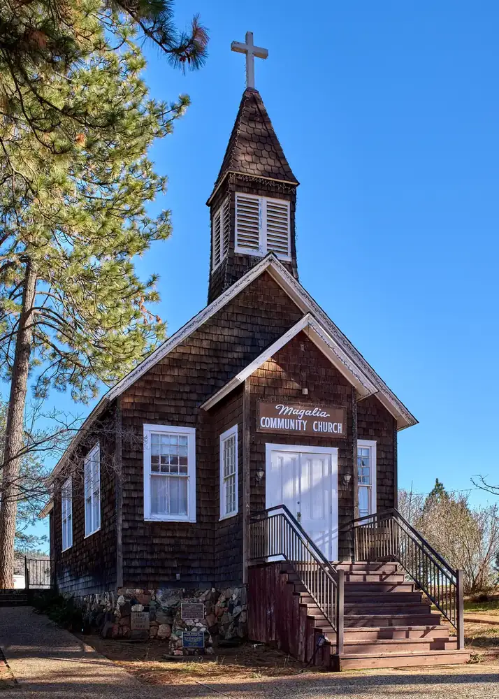 The historic wooden Magalia Community Church surrounded by tall pines