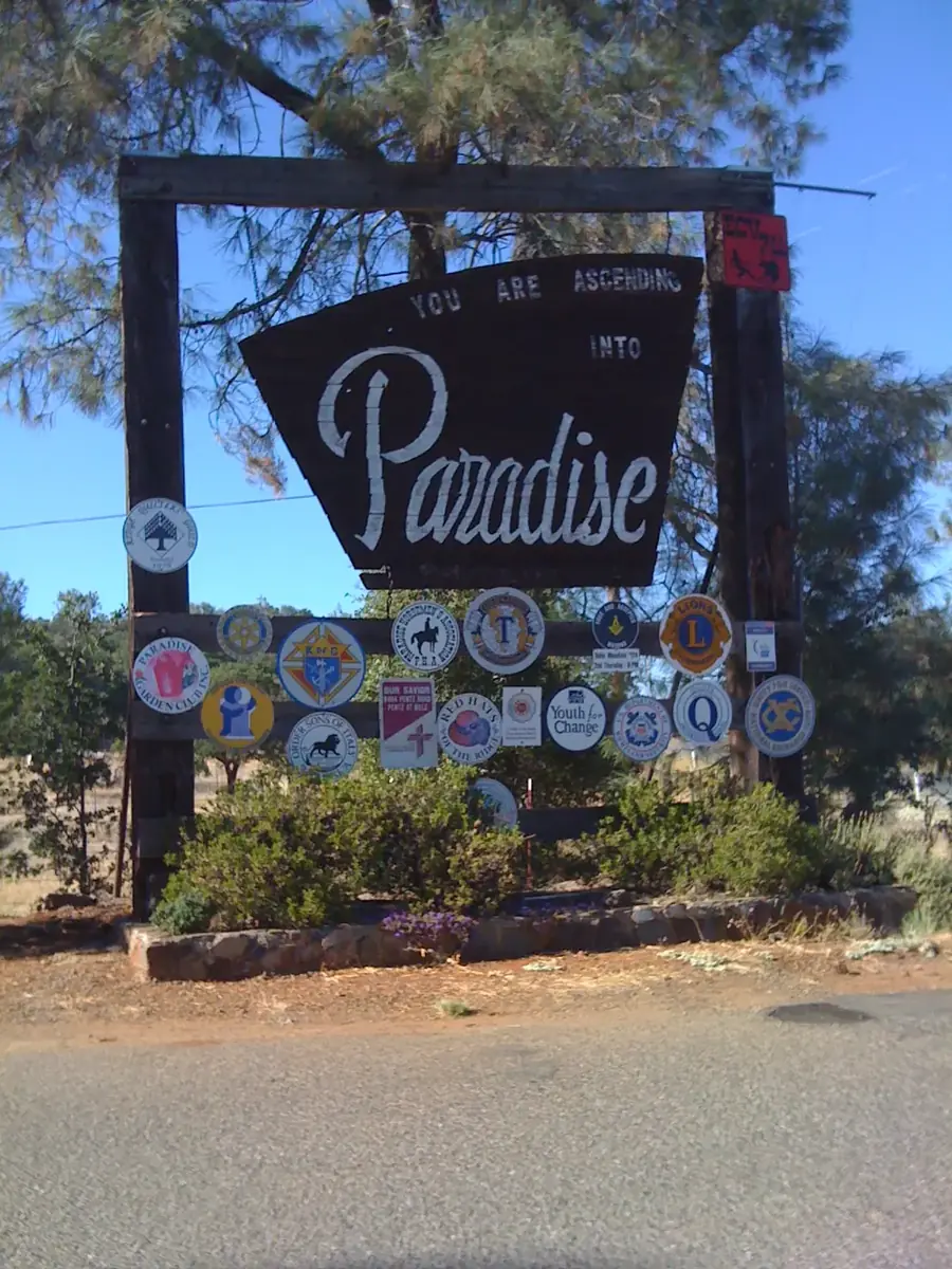 The wooden welcome sign reading You Are Ascending Into Paradise beside a foothill road