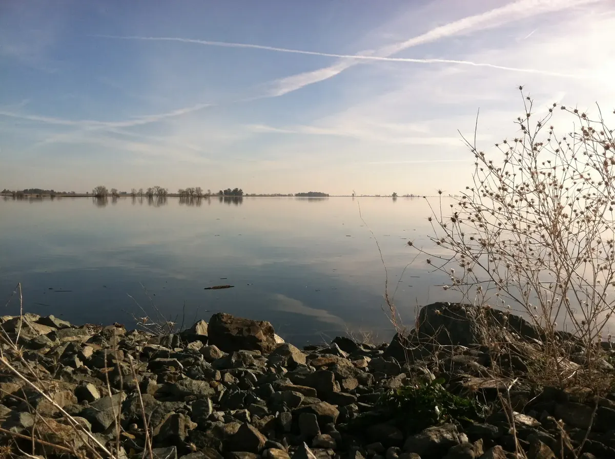 The flat Thermalito Afterbay with still water and level valley ground stretching to the horizon